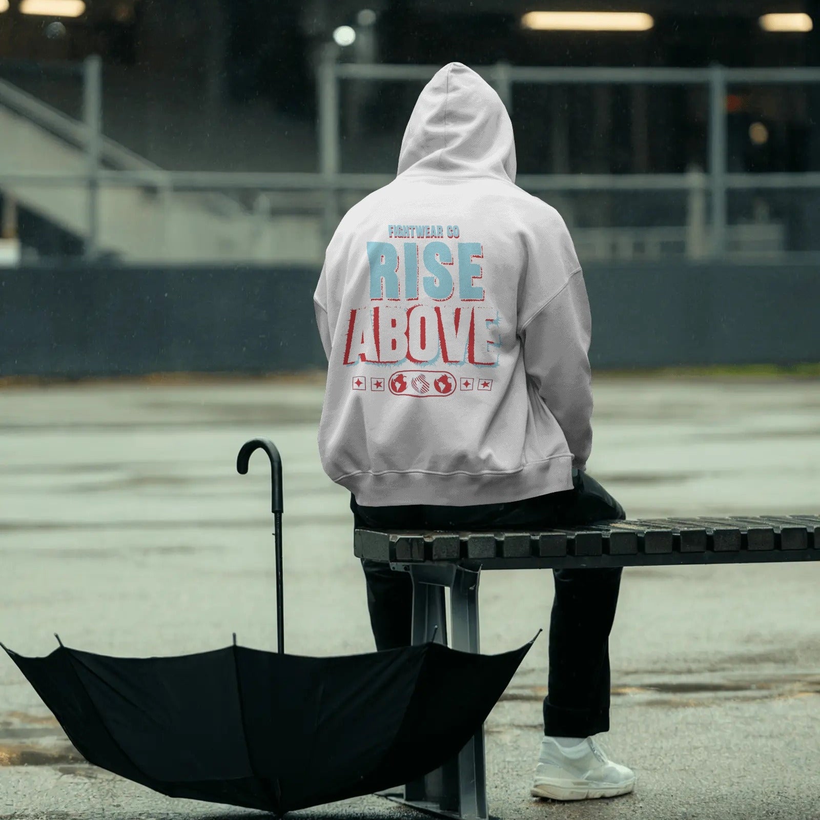 rainy-day-hoodie-mockup-person-sitting-on-metal-bench-with-open-umbrella-moody-outdoor-setting-0789